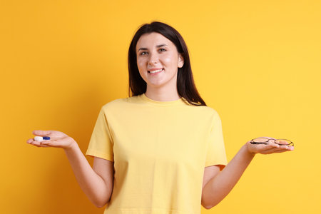 Young woman choosing between glasses and contact lensesの写真素材