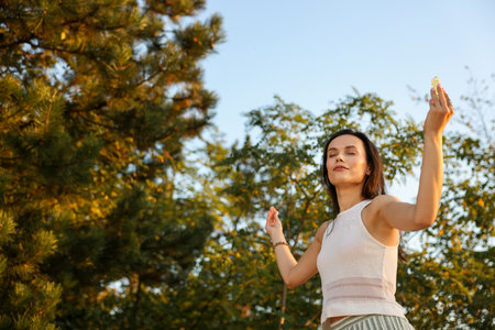 Woman meditating with crystal to heal or restore her aura outdoors, low angle view. Space for textの写真素材