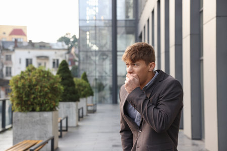 Young man in suit suffering from nausea outdoors, space for textの写真素材