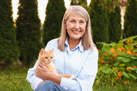 Senior woman with her cute cat in gardenの写真素材