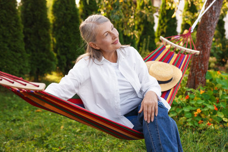 Beautiful senior woman resting in hammock outdoorsの写真素材