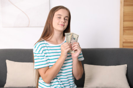 Girl with pocket money on sofa at homeの写真素材