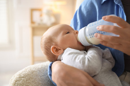 Mother feeding her little baby with bottle at home, closeupの写真素材