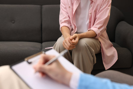 Professional psychologist working with patient and writing in clipboard in office, closeupの写真素材
