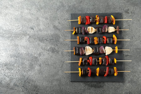 Skewers with tasty grilled vegetables on gray table, top view. Space for textの写真素材