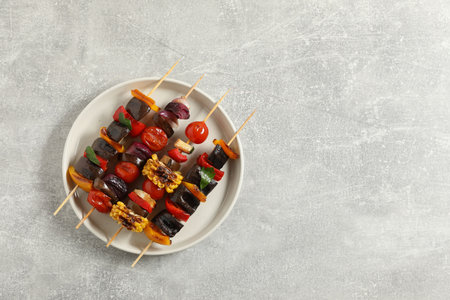Skewers with tasty grilled vegetables on gray table, top view. Space for textの写真素材