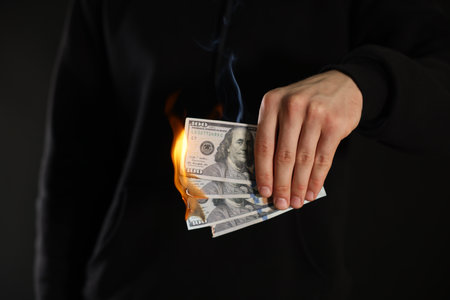 Man burning dollar banknotes on black background, closeupの写真素材