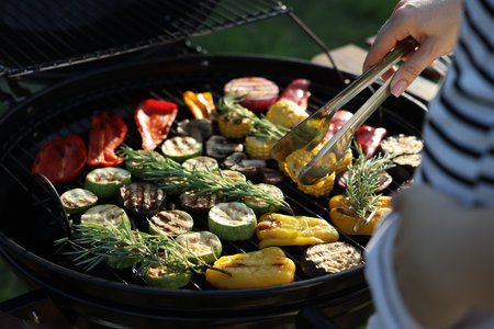 Vegetarian barbeque. Woman cooking vegetables on grill outdoors, closeupの写真素材