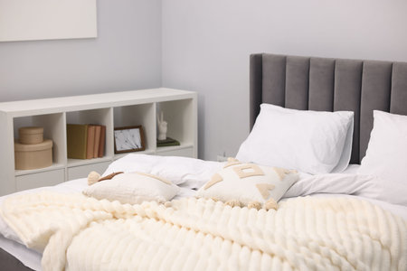 Large bed with lines and shelving unit near gray wall in bedroomの写真素材