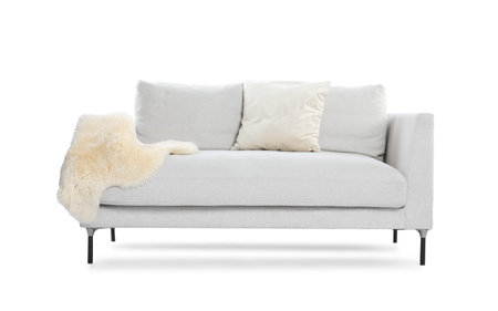 Soft sofa with pillows and faux fur isolated on whiteの写真素材