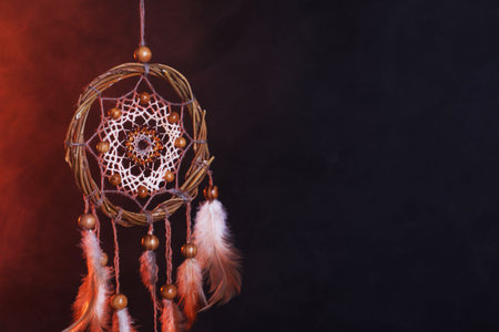 Beautiful dream catcher hanging in color lights on dark background with smoke. Space for textの写真素材