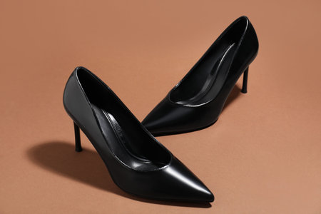 Pair of stylish high heeled shoes on brown backgroundの写真素材