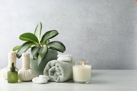Beautiful spa composition with herbal bags and burning candle on white table, space for textの写真素材