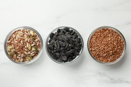 Different seeds in bowls on white table, flat layの写真素材
