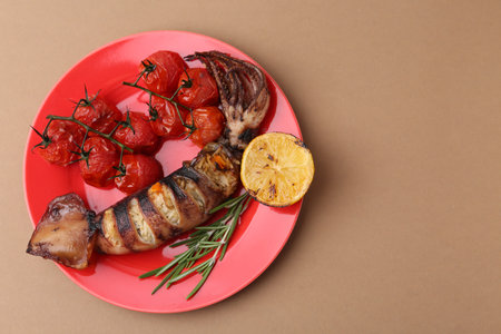 Tasty stuffed squid, rosemary, lemon and tomatoes on beige background, top view. Space for textの写真素材