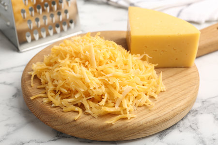 Grated and piece of cheese with grater on white marble table, closeupの写真素材