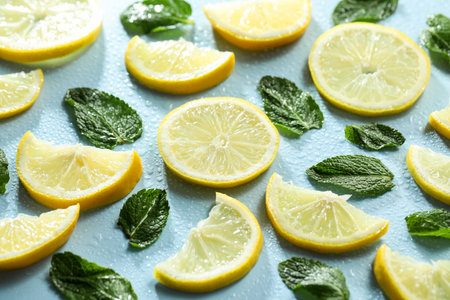 Slices of lemon, mint and water drops on light blue background, closeupの写真素材