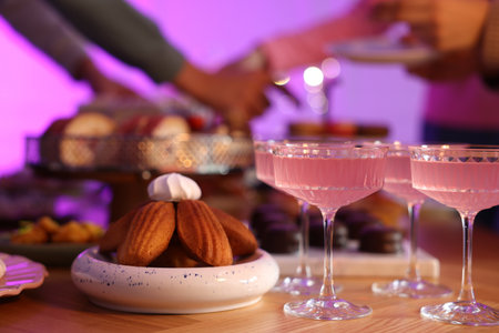 Glasses of cocktails and people with delicious desserts at buffet table, selective focusの写真素材