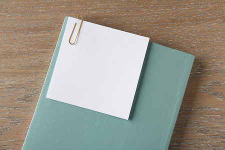 Blank note with clip and notebook on wooden table, top view. Space for textの写真素材