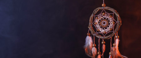 Beautiful dream catcher hanging in color lights on dark background, closeup. Space for textの写真素材