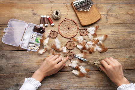 Woman making beautiful dream catcher at wooden table, top viewの写真素材