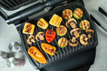 Electric grill with delicious vegetables on light table, flat layの写真素材