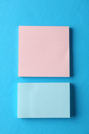 Blank colorful notes on light blue background, top view. Space for text