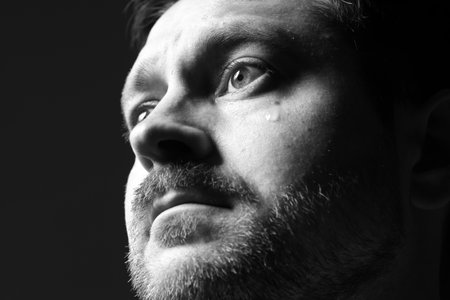 Sad man crying on dark background, space for text. Black and white effectの写真素材