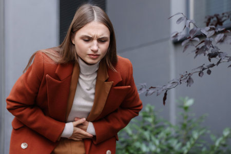 Young woman suffering from stomach ache and nausea outdoors, space for textの写真素材