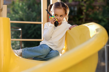 Little girl playing with walkie talkie toy at playgroundの写真素材