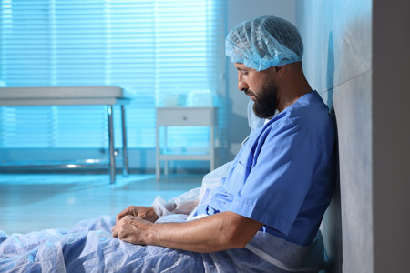 Tired doctor near wall in clinic during night shiftの写真素材