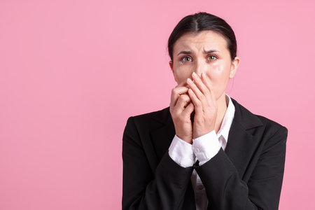 Businesswoman in suit crying on pink background. Space for textの写真素材
