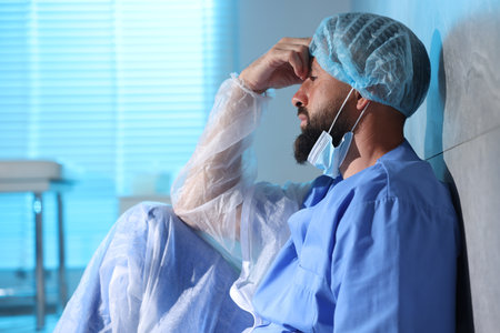 Tired doctor near wall in clinic during night shiftの写真素材