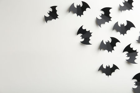 Halloween decor. Black paper bats on white background, flat lay. Space for text