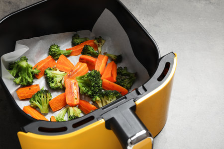 Grilled vegetables in air fryer basket on gray table, closeupの写真素材