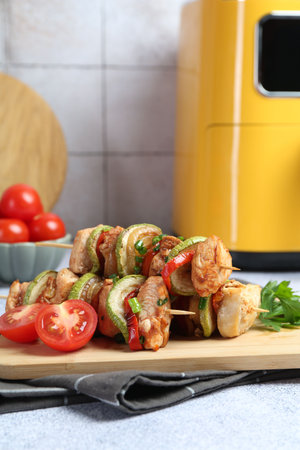 Tasty skewers with chicken, parsley, vegetables and air fryer on light gray table, closeupの写真素材
