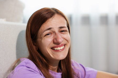 Beautiful woman laughing through tears indoors, closeupの写真素材