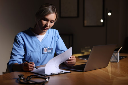 Medical assistant working at table in clinic during night shiftの写真素材
