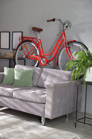 Red bicycle, sofa and houseplant in roomの写真素材