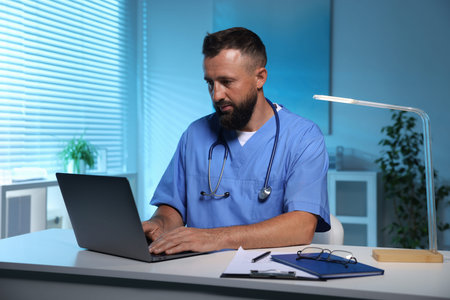 Doctor working on laptop at table in clinic during night shift