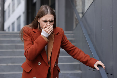 Young woman suffering from nausea on city streetの写真素材