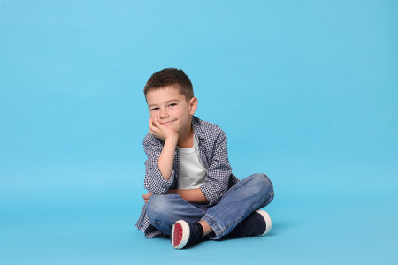 Cute little boy on light blue backgroundの写真素材