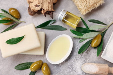 Flat lay composition with handmade soap bars, olives and oil on gray textured tableの写真素材