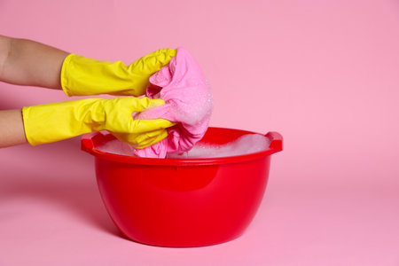 Woman washing clothes in plastic basin on pink background, closeupの写真素材