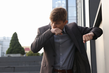 Young man in suit suffering from nausea outdoorsの写真素材