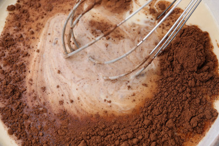 Adding cocoa powder into bowl with dough, closeupの写真素材