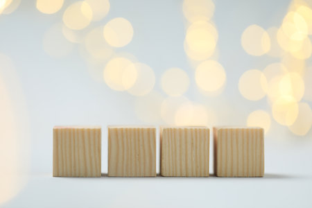 Blank wooden cubes on light background with blurred lights, space for text. Bokeh effectの写真素材