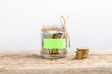 Jar with blank note and money on wooden table against white backgroundの写真素材