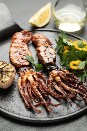 Tasty cooked squids served with lemon, garlic and salad on black table, closeupの写真素材
