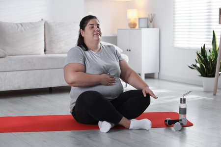Woman in sportswear deep breathing on yoga mat at homeの写真素材